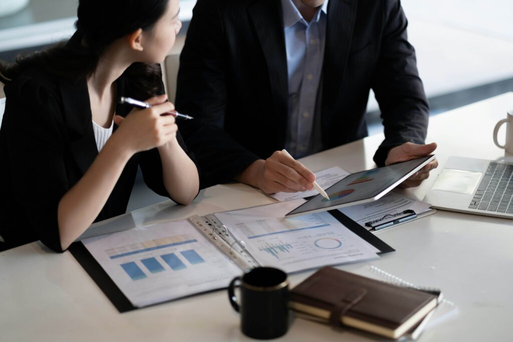 Accountancy for Business. Image of man and woman in suit looking and pointing at iPad