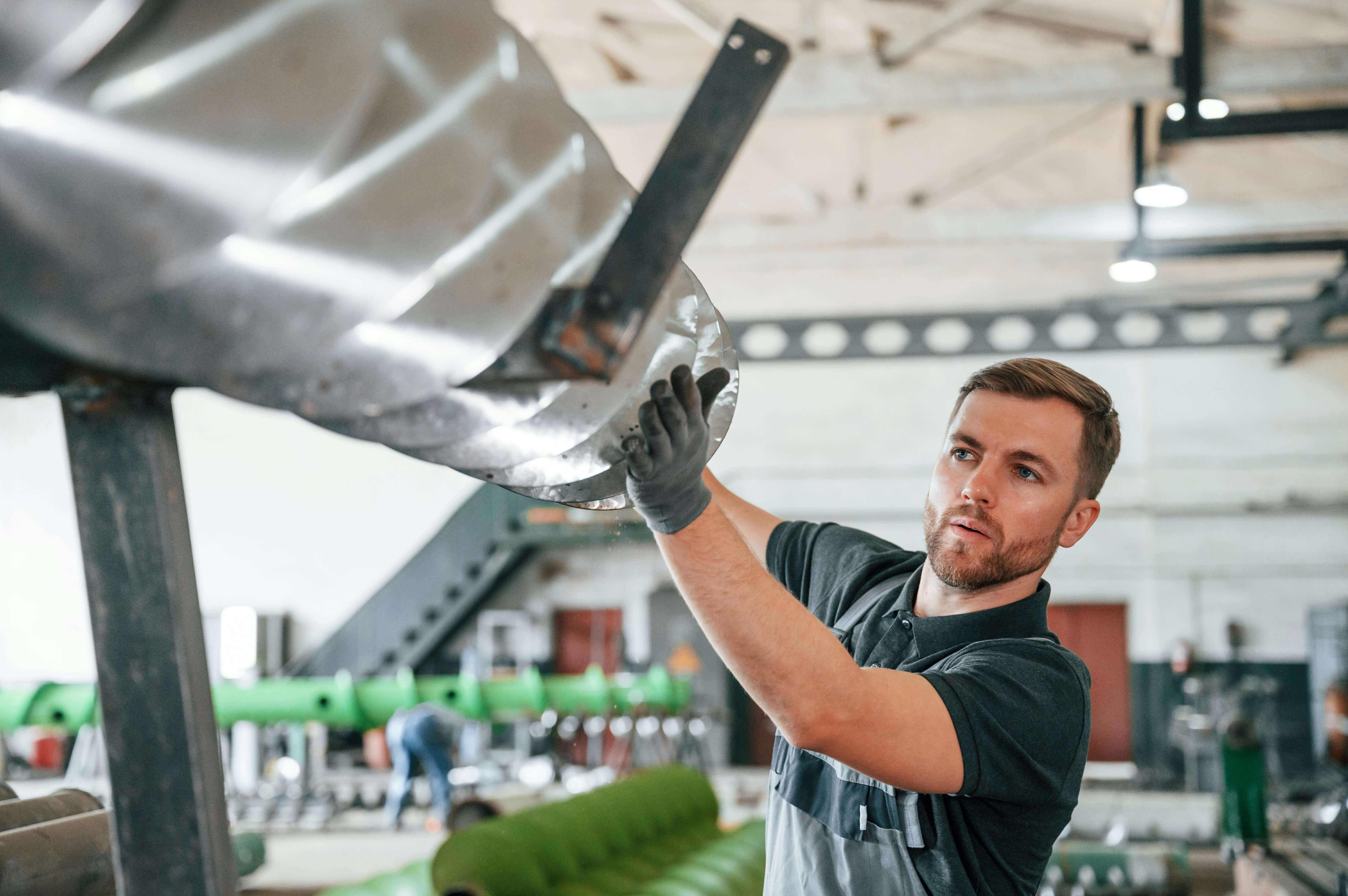 Bevan Buckland Accountants for Manufacturing. Man in overalls and gloves moving metal sheet